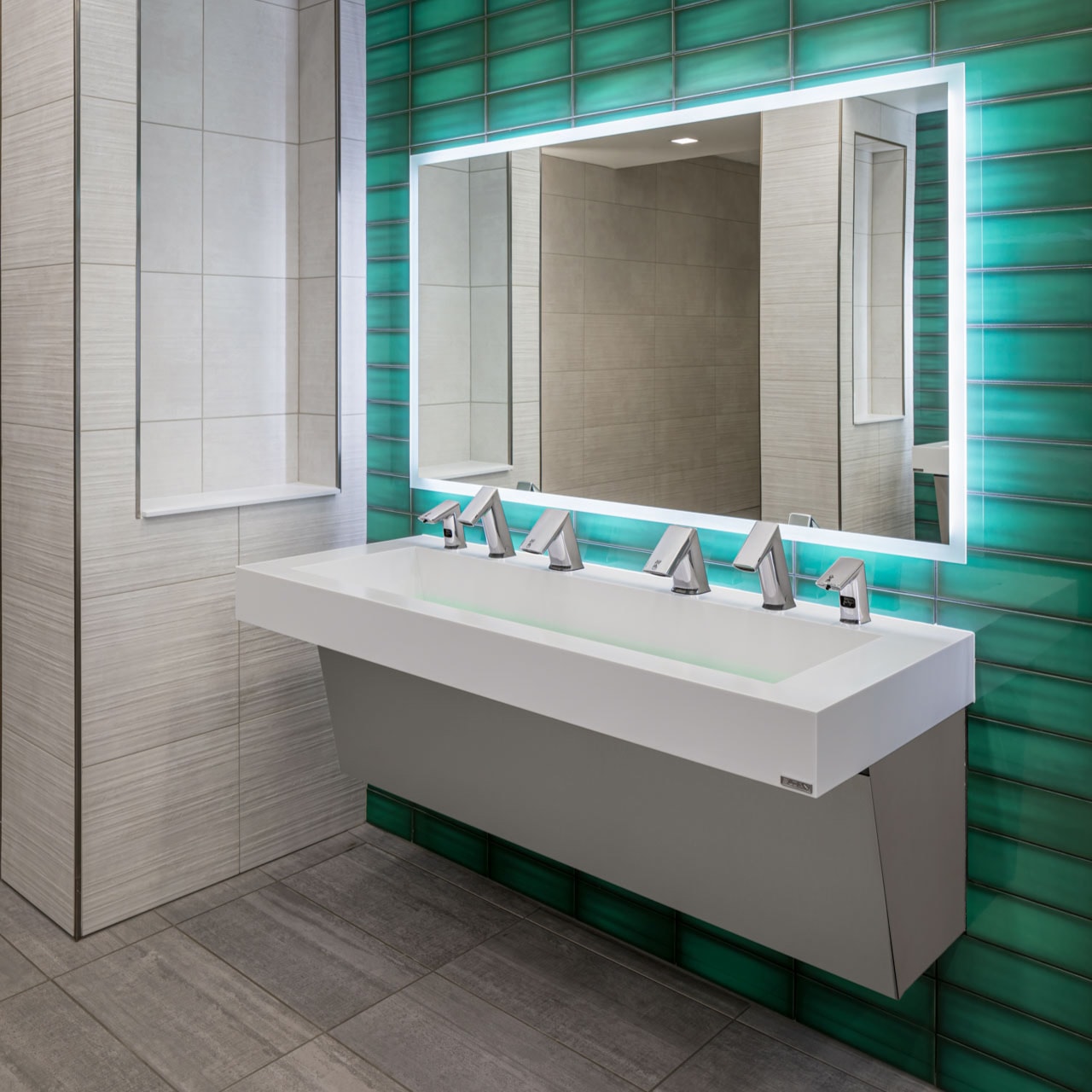 Modern commercial restroom with illuminated mirror, marble sink, and city skyline view